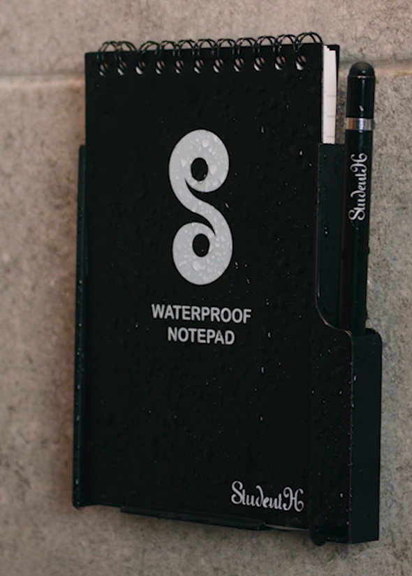 Black waterproof notepad with a logo on a tiled wall